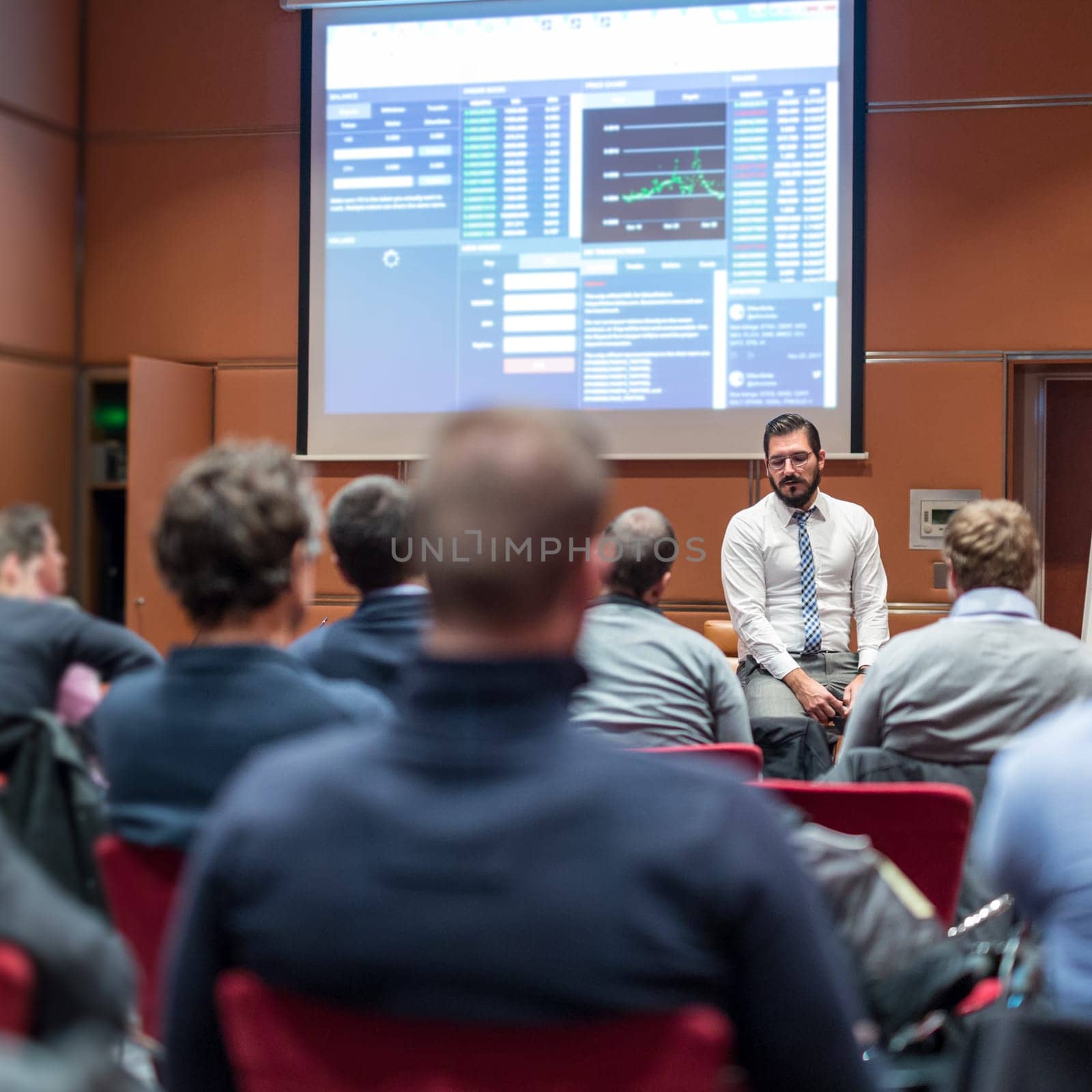 Public Speaker Giving a Talk at Business Meeting. Audience in the conference hall. Skilled coach asks questions to participants of business training. Business and Entrepreneurship concept.