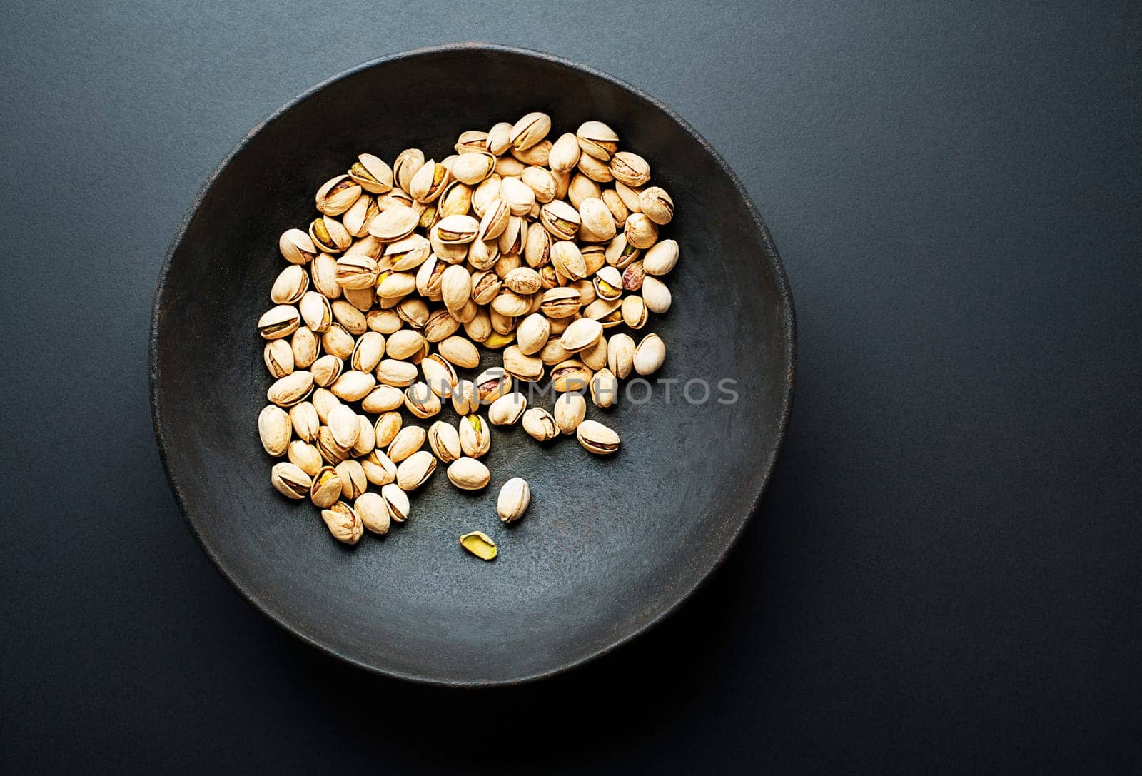 Bowl with pistachios on a black table background
