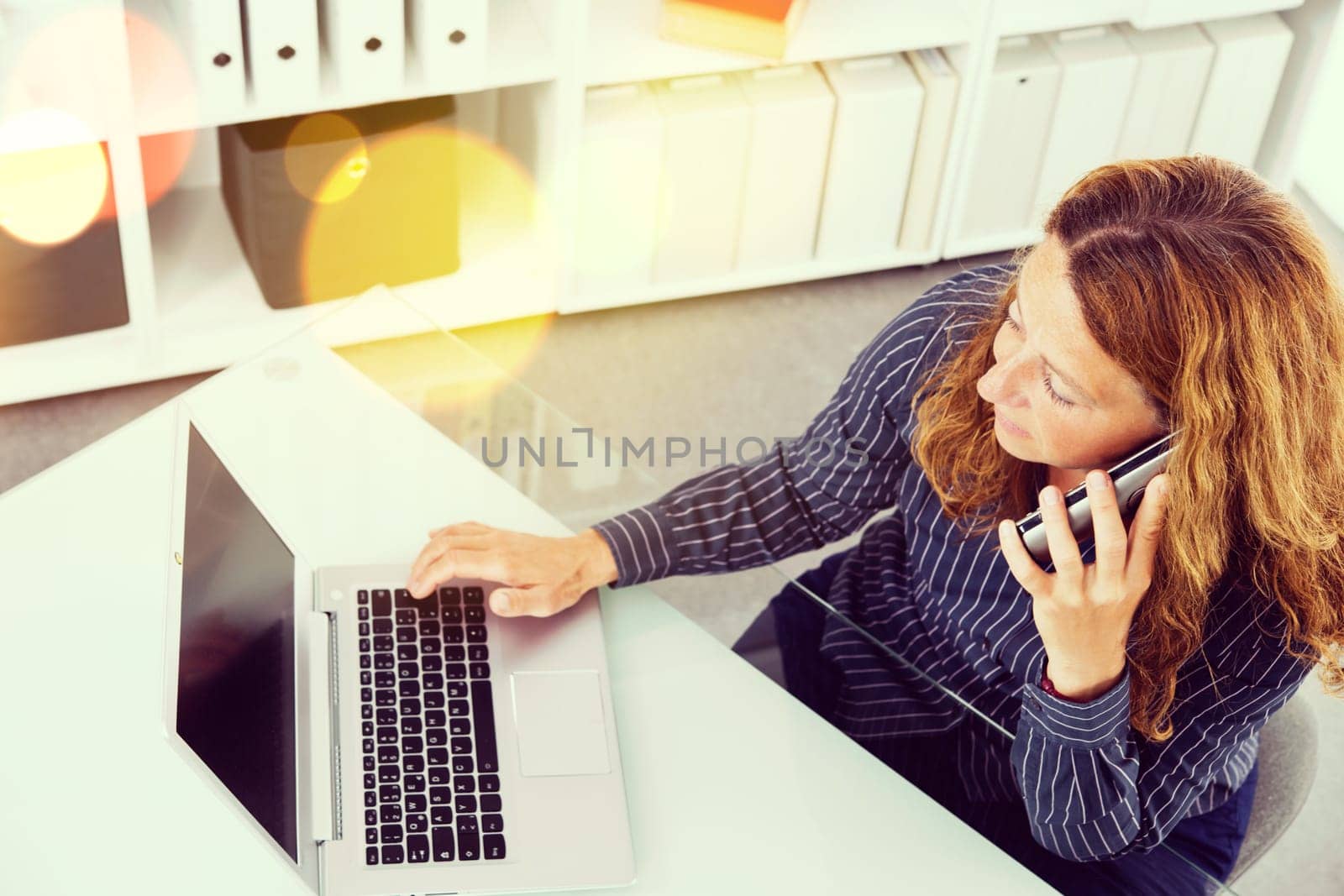 brown-haired businesswoman working with computer and calling in the office