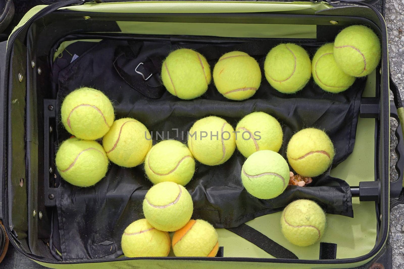 Several used green tennis balls in suitcase
