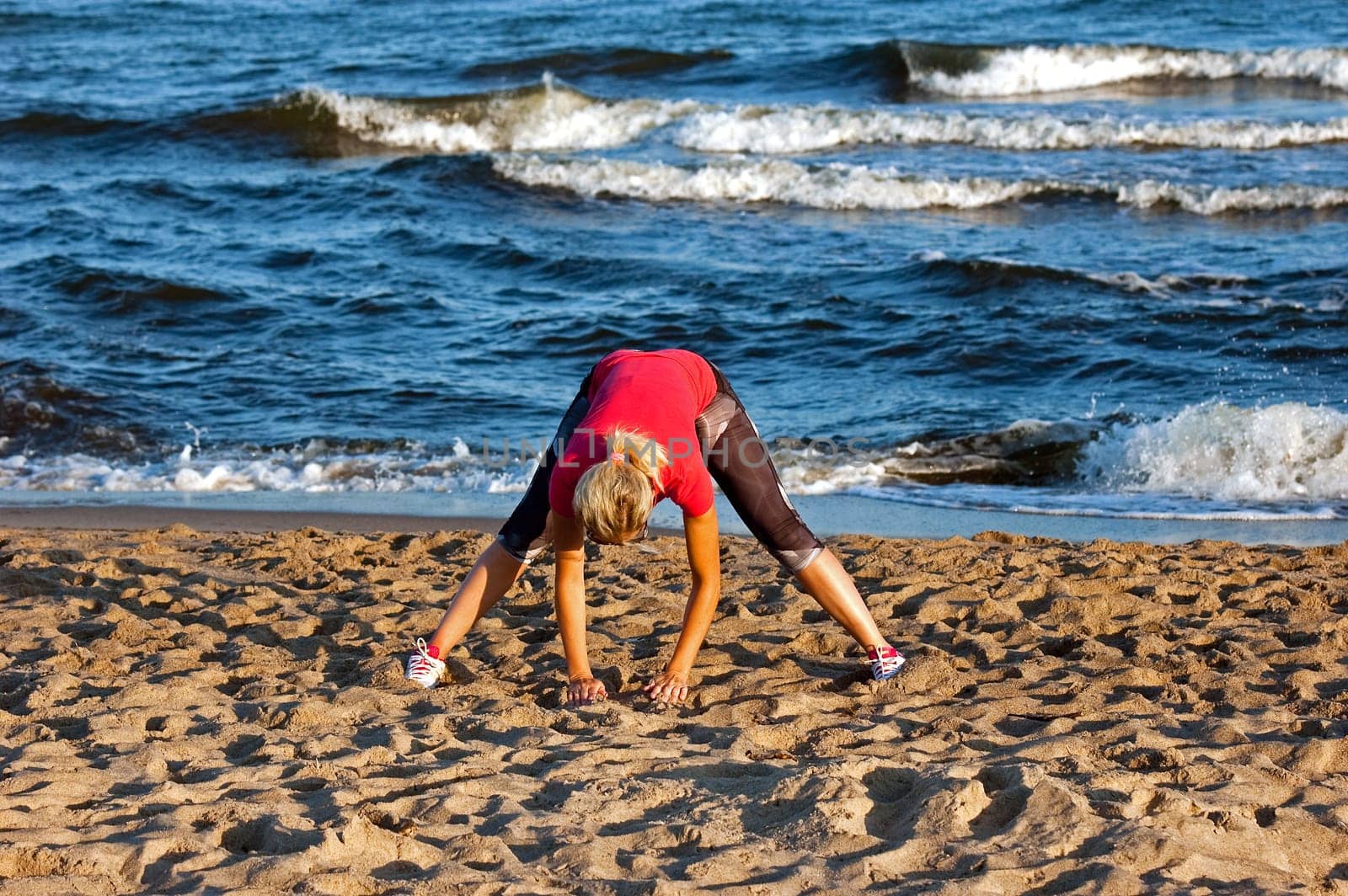 young beautiful sportswoman doing exercises on beach