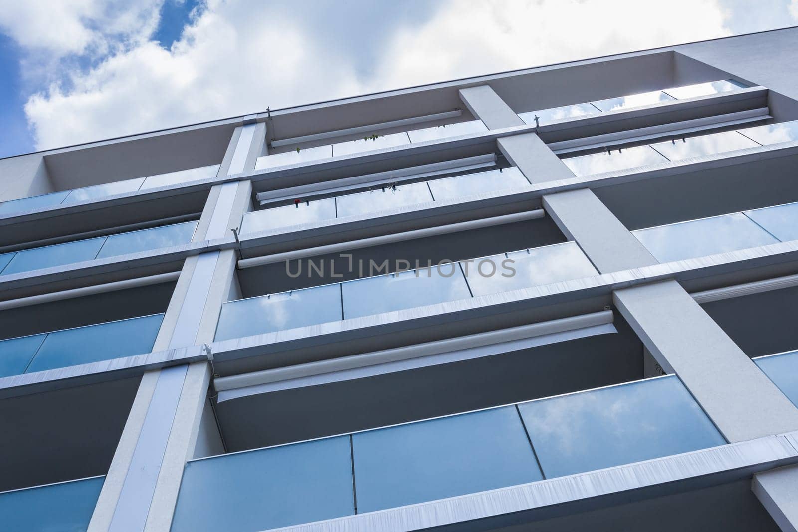 Modern new apartment with concrete exterior walls and large glass balconies in Italy.