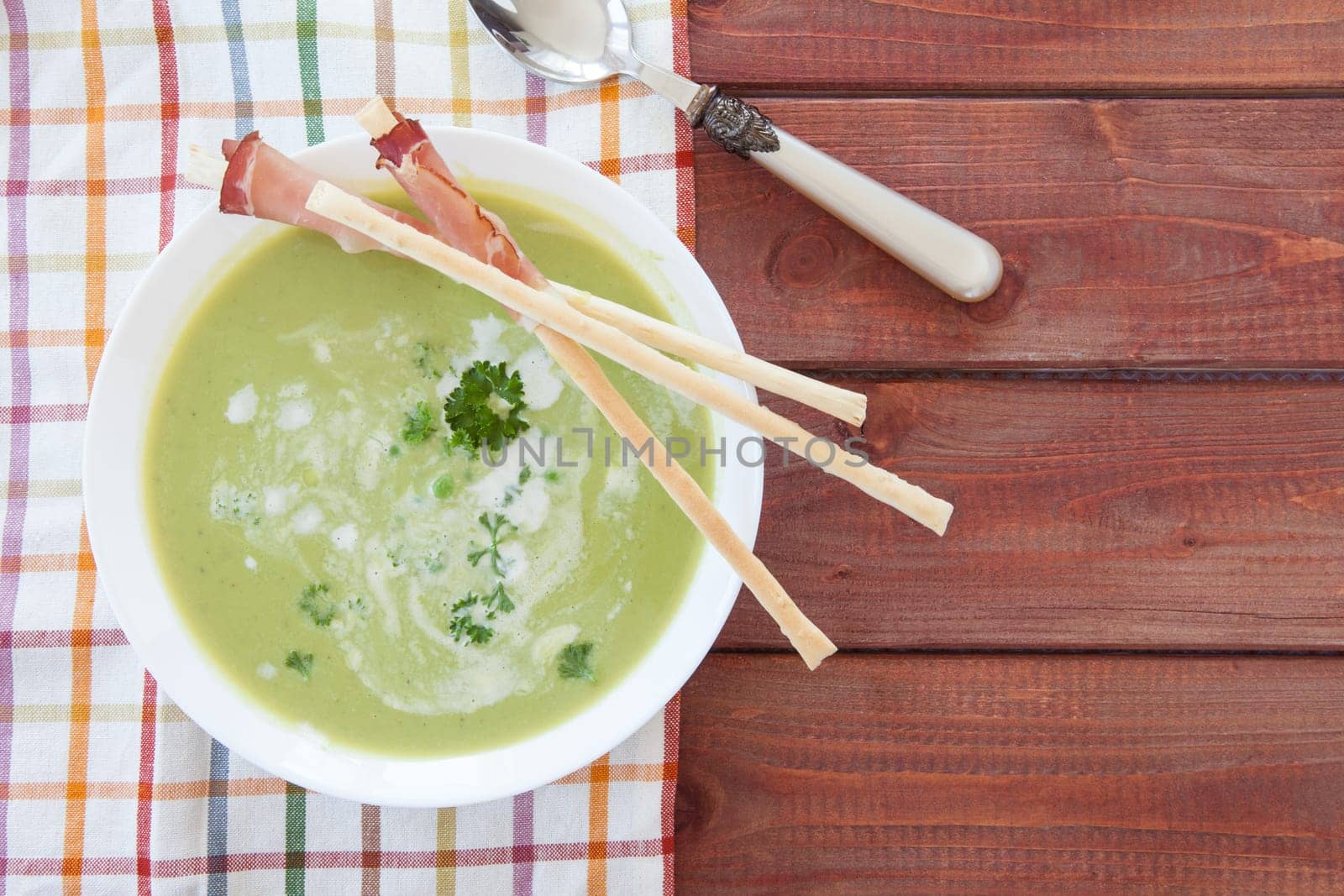Homemade creamy pea soup and bread sticks with smoked ham