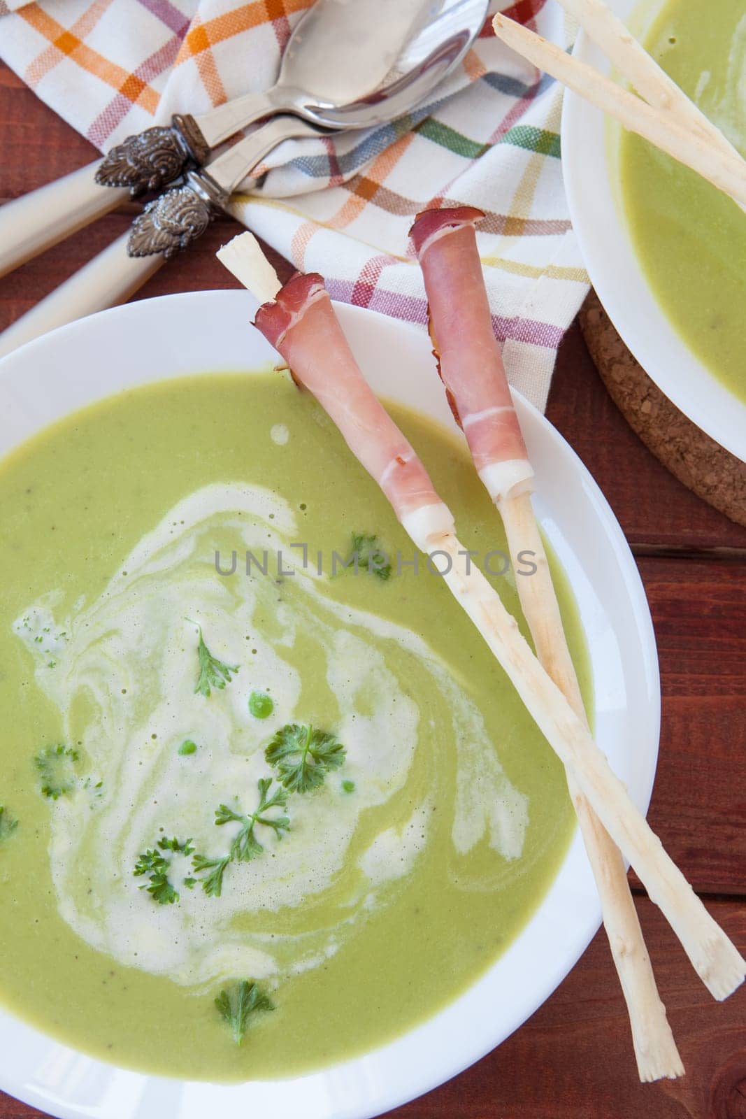 Homemade creamy pea soup and bread sticks with smoked ham
