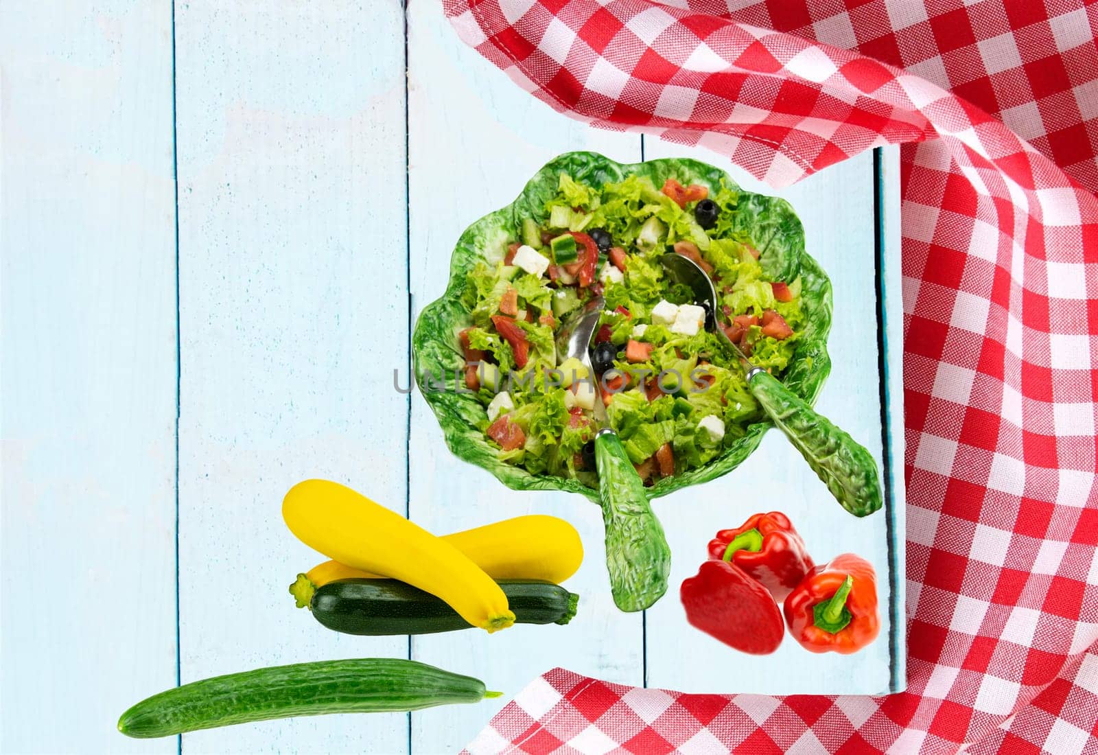 Food recipe template. Healthy fresh vegetarian vegetable spring salad in ceramic salad bowl and zucchini, cucumber and paprika on table. Health care, diet and nutrition concept.