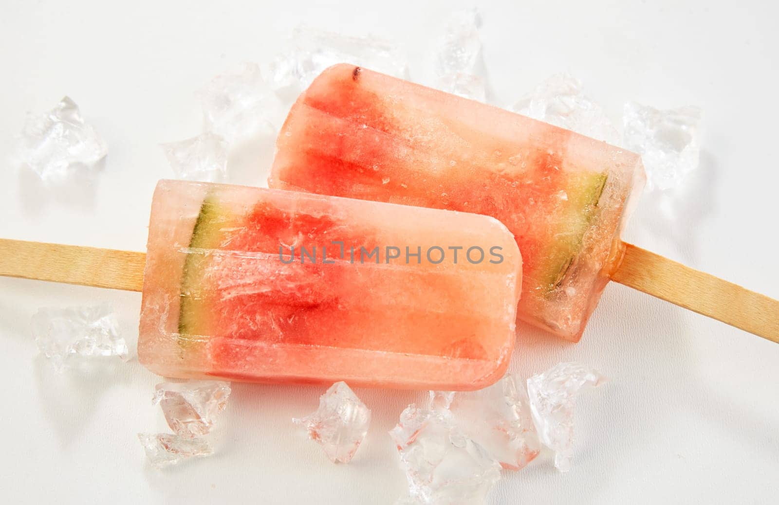 Two healthy iced popsicles with fresh watermelon for a tasty treat for kids in summer close up on a bed of ice