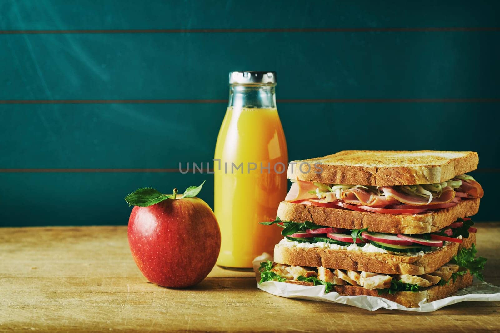 Lunch food set consist of sandwich, juice, apple on wooden table