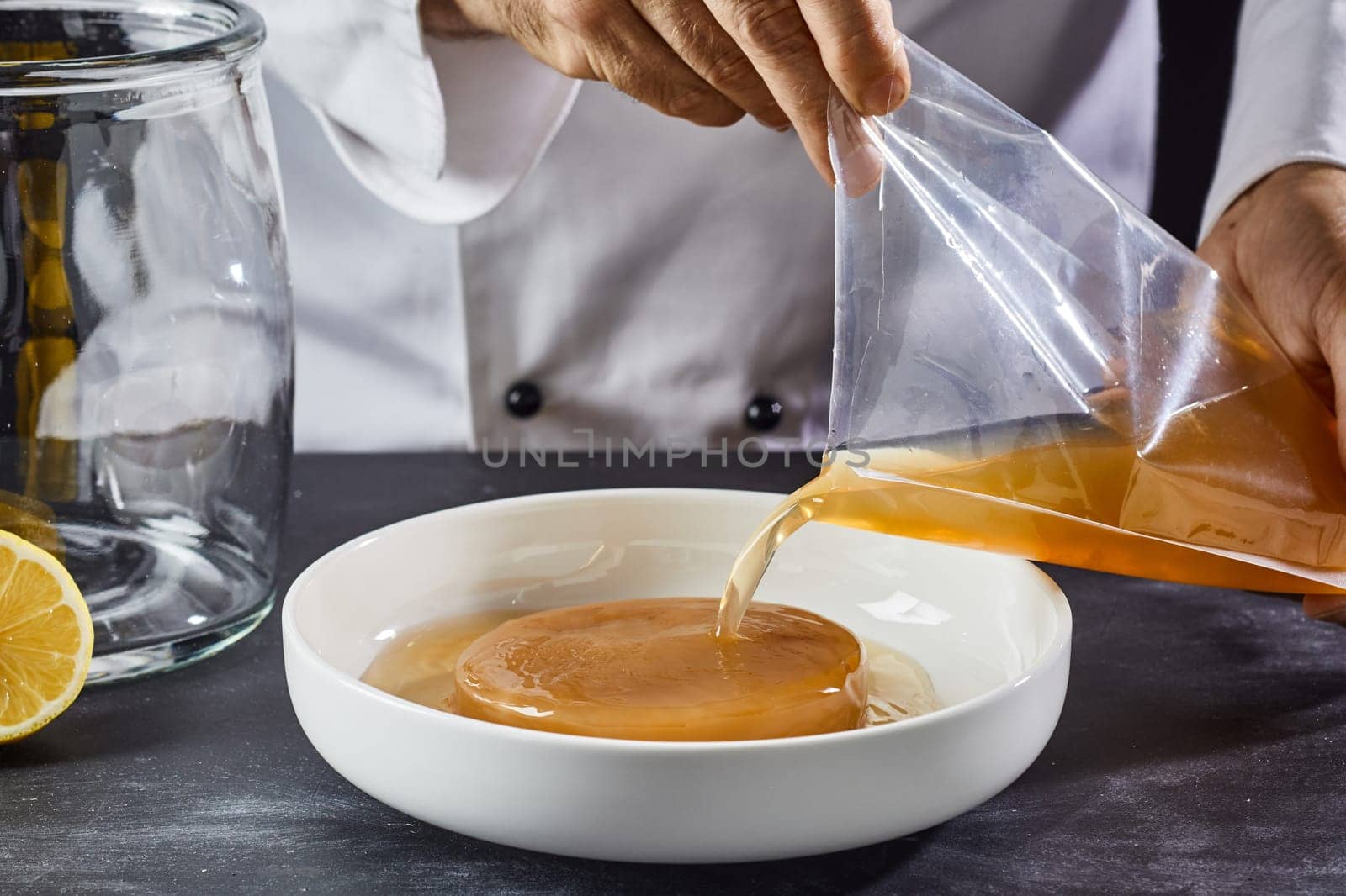 Man activating the mother, fungus or scoby in a dish pouring the starter liquid from a bag to begin the fermentation process when making homemade kombucha