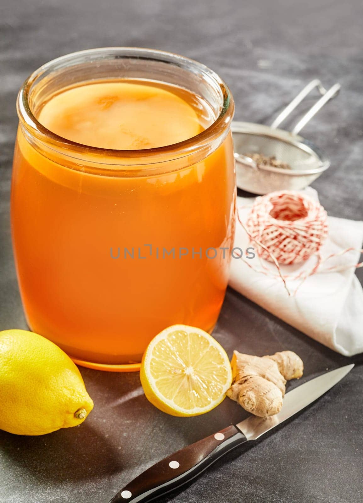 Glass jar of ready kombucha with a scoby, fungus or mother fermenting the sweetened black tea