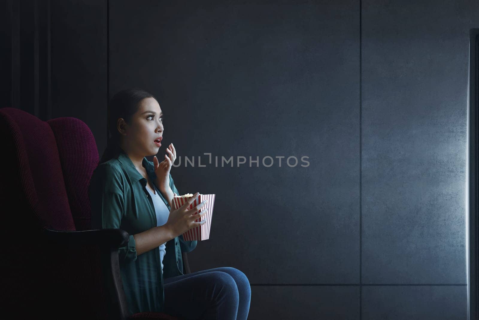 Portrait of asian woman with popcorn watching horror movie at home
