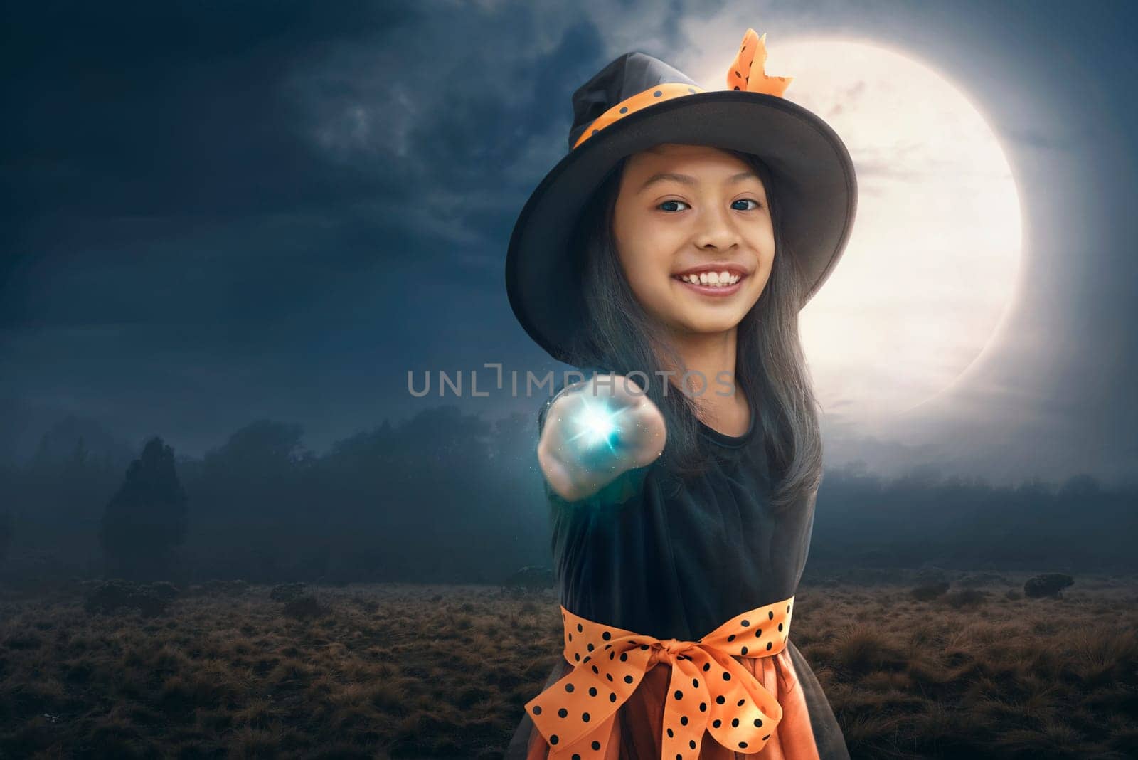Smiling asian child girl using her magic power with moonlight background