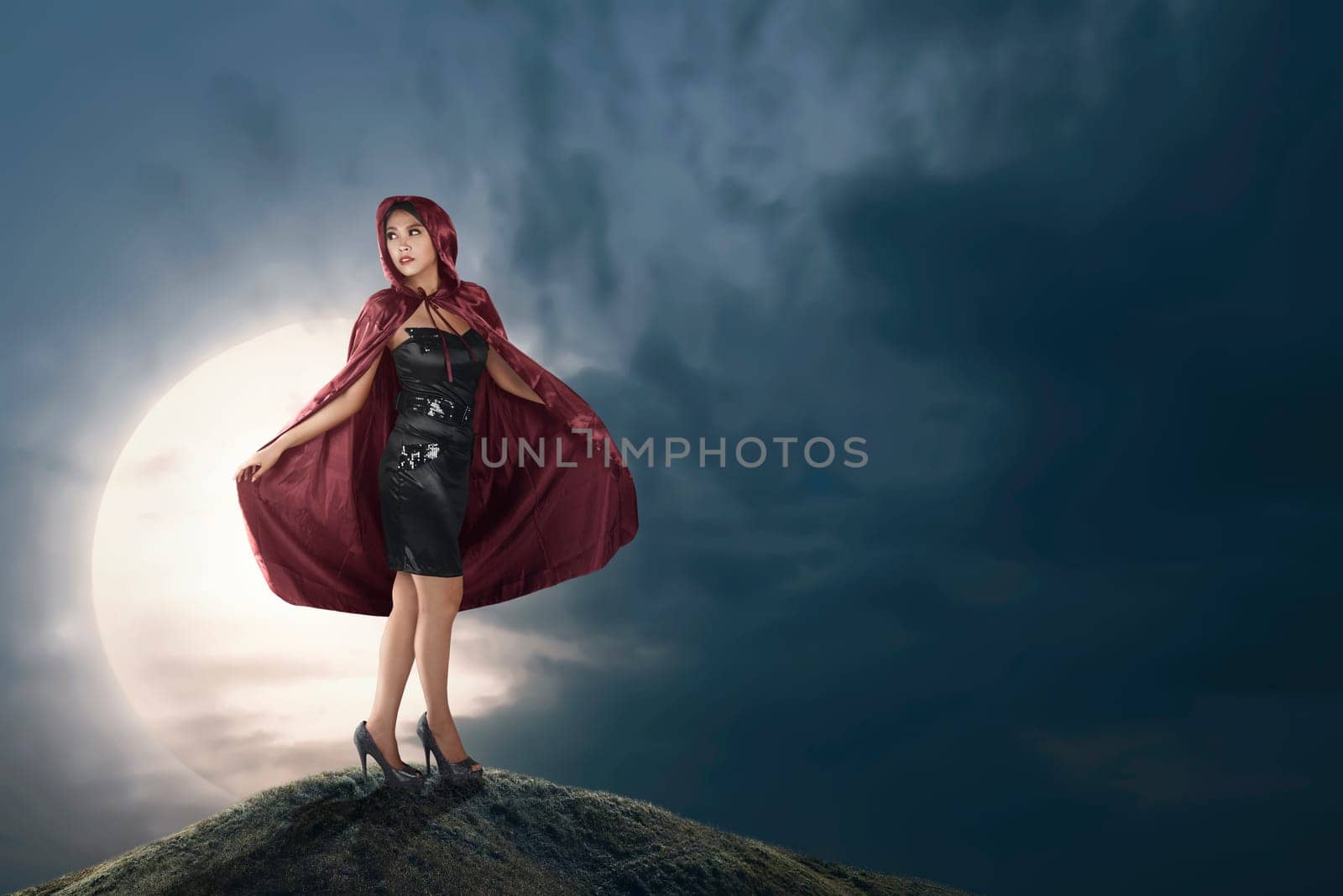 Pretty asian witch woman with red hooded cloak on the midnight
