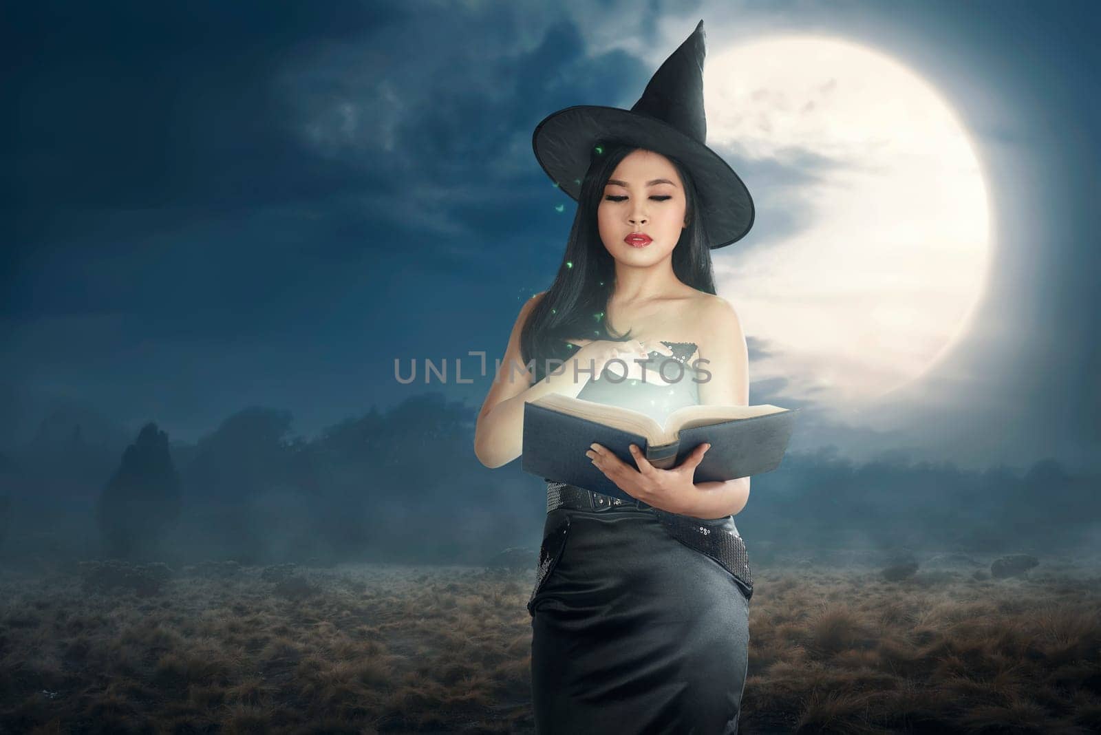 Young asian witch woman reading the spell books on the night