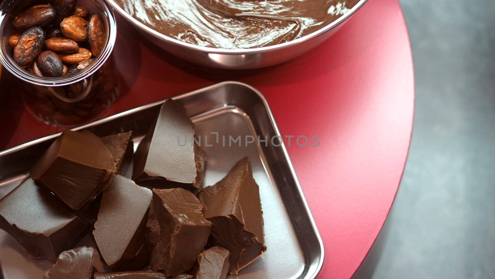 Close-up images of chocolate bar top view angle and cocoa seed with bowl of dark brown cream milk swirling by handmade for represent one of delicious sweet in the World