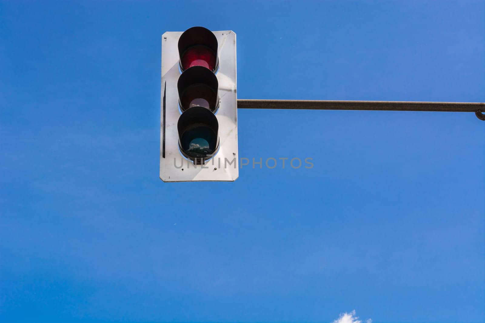 A traffic light and a surveillance camera on a pole mounted on the street.