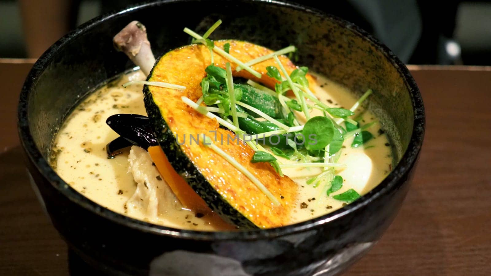 Close-up images of yellow color soup curry with chicken, pork and vegetable in bowl which famous traditional food menu and only found in Hokkaido Sapporo district of Japan