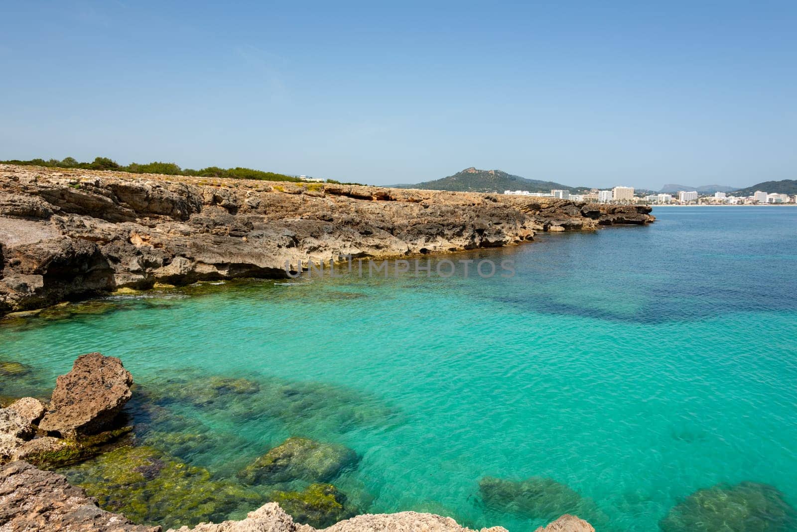 View over the clear turquoise waters of the Mediterranean to the beach of Cala Millor on the Spanish Mediterranean island Mallocra