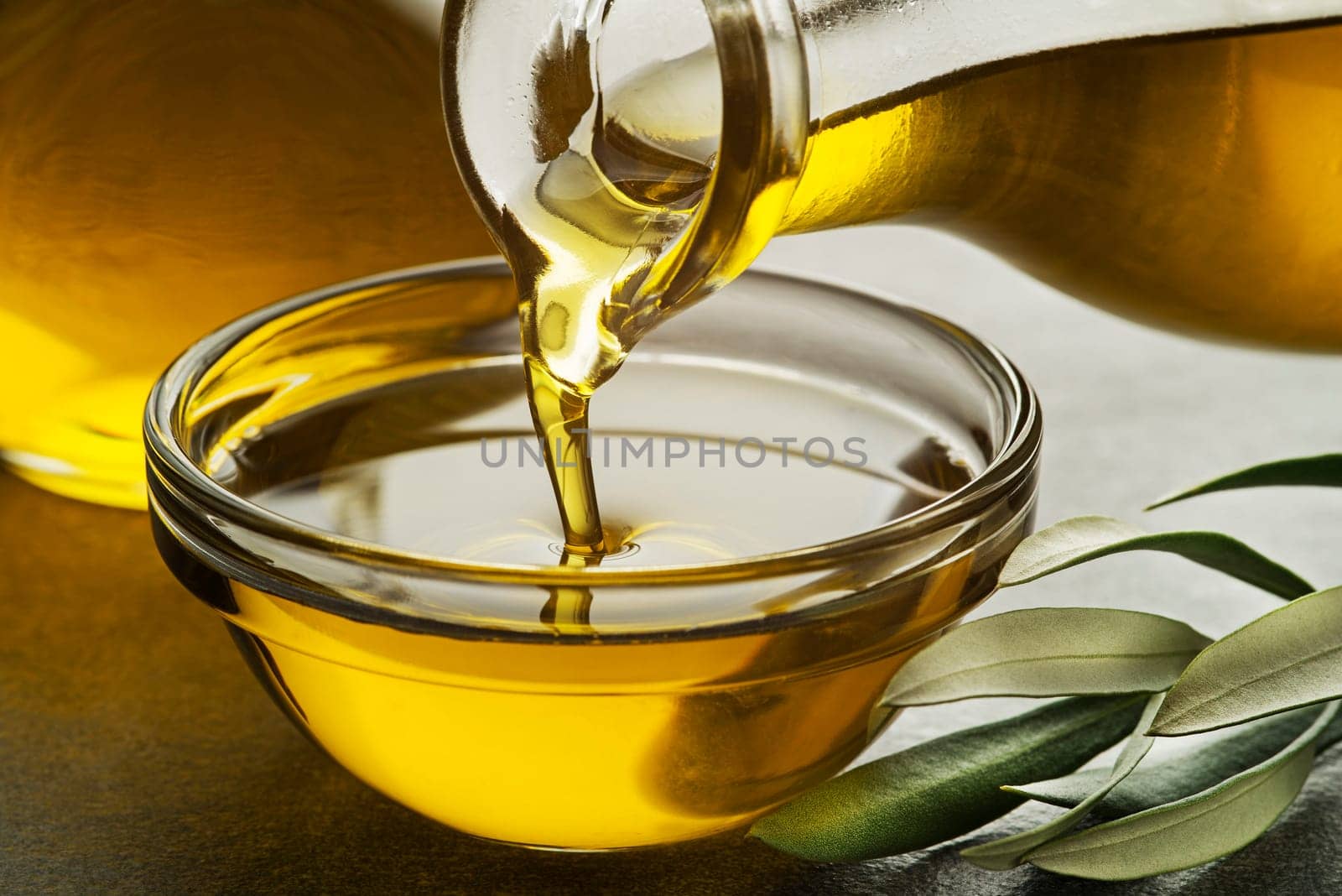 Bottle pouring virgin olive oil in a bowl close up