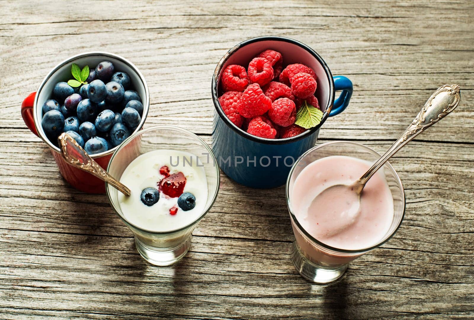 Bowl of fresh mixed berries and yogurt with fresh blueberries, raspberries served on a wooden table