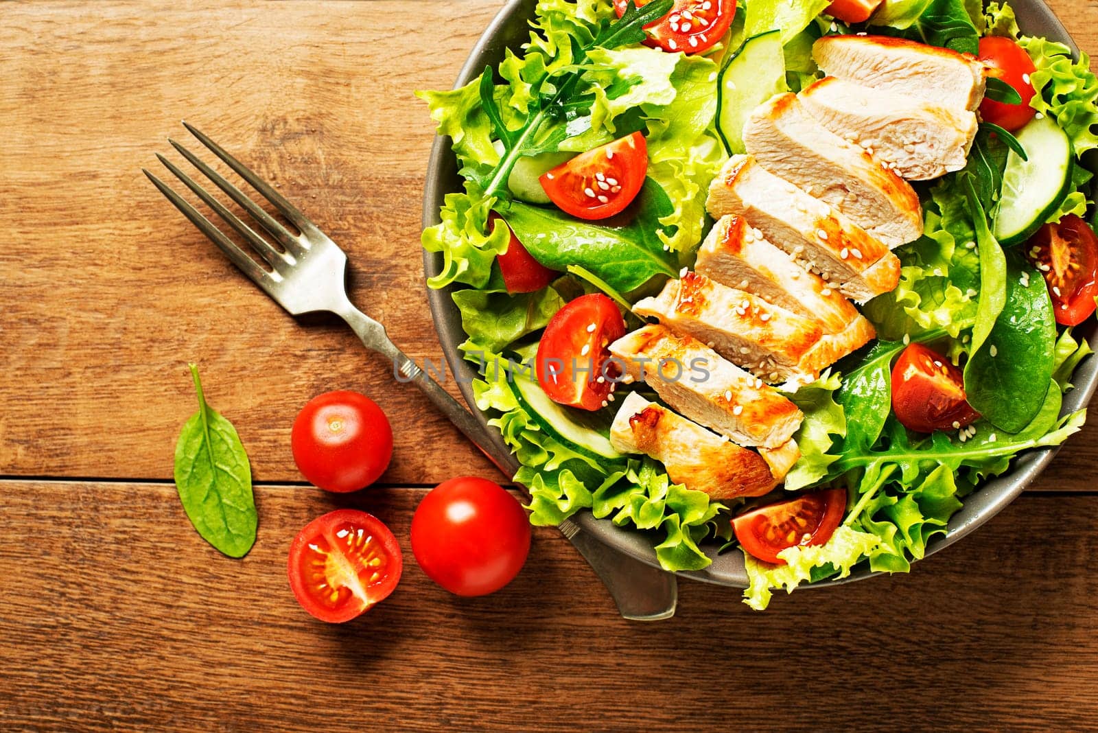 Fresh green salad with chicken breast and tomato. Top view