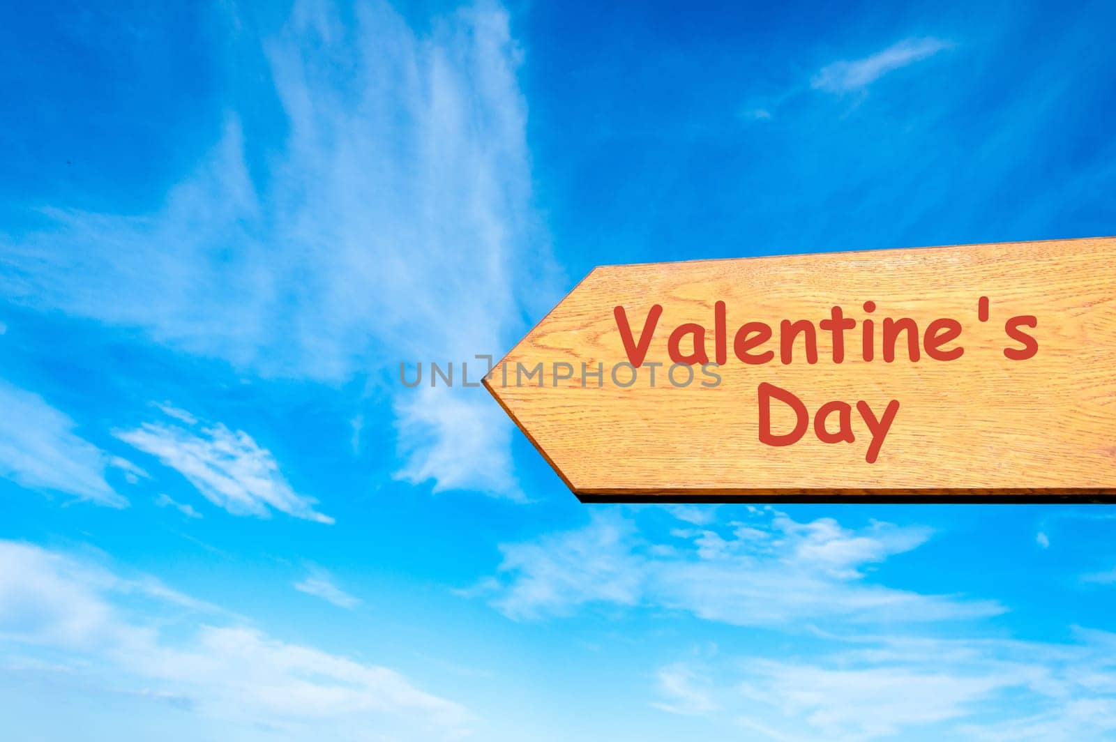 Wood arrow sign against clear blue sky with Valentines Day message, Love conceptual image