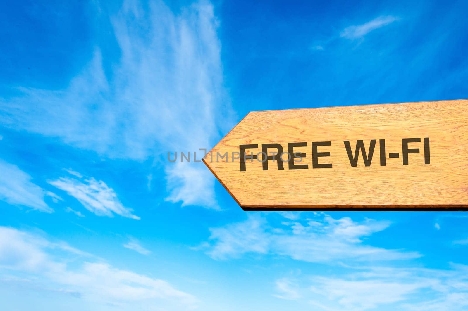 Wood arrow sign against clear blue sky with Free Wi-Fi message