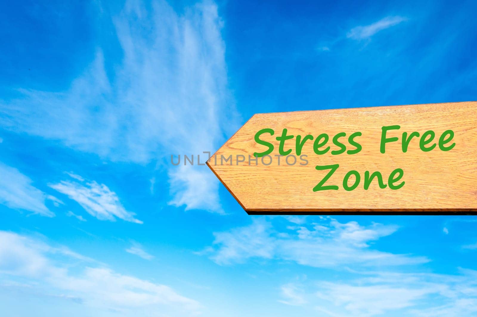 Wood arrow sign against clear blue sky with Stress Free zone message