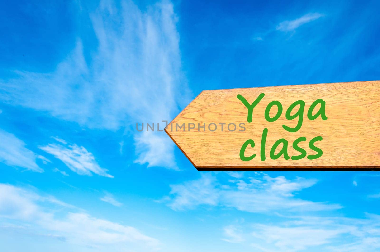 Wood arrow sign against clear blue sky with Yoga Class message
