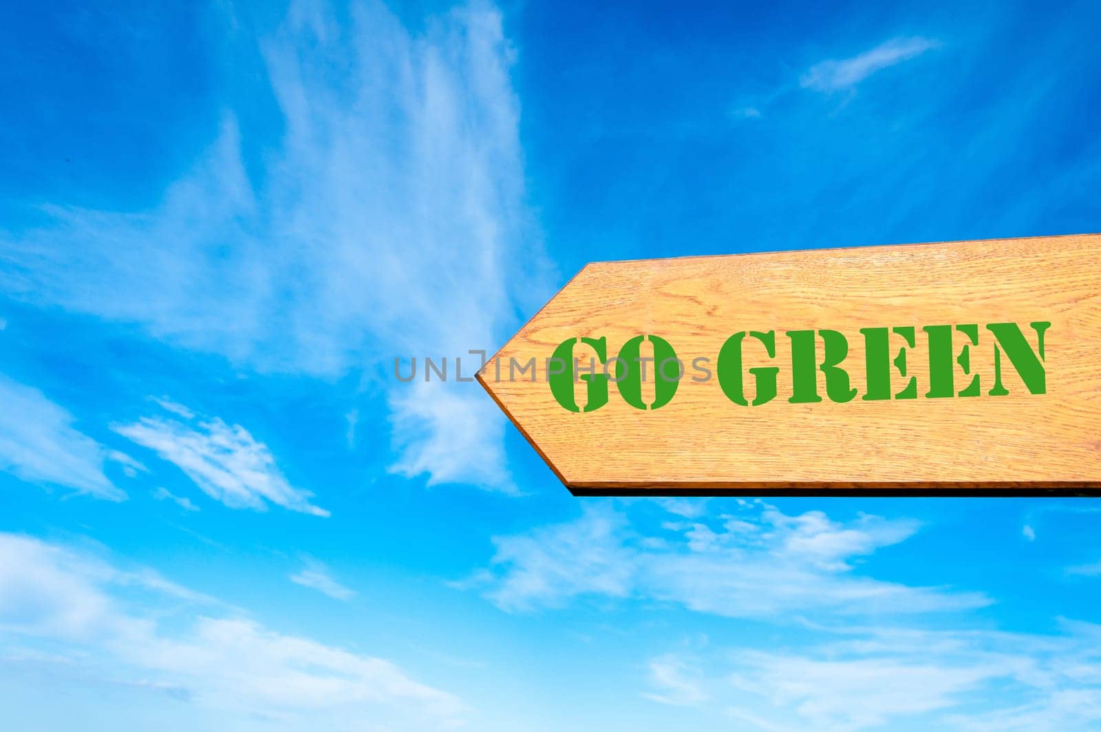 Wood arrow sign against clear blue sky with Go Green message, Eco concept