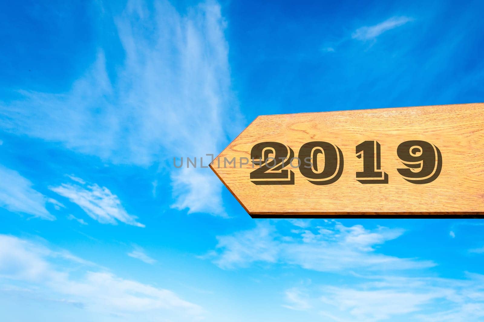 Wood arrow sign against clear blue sky with year 2019 text, Happy New Year conceptual image