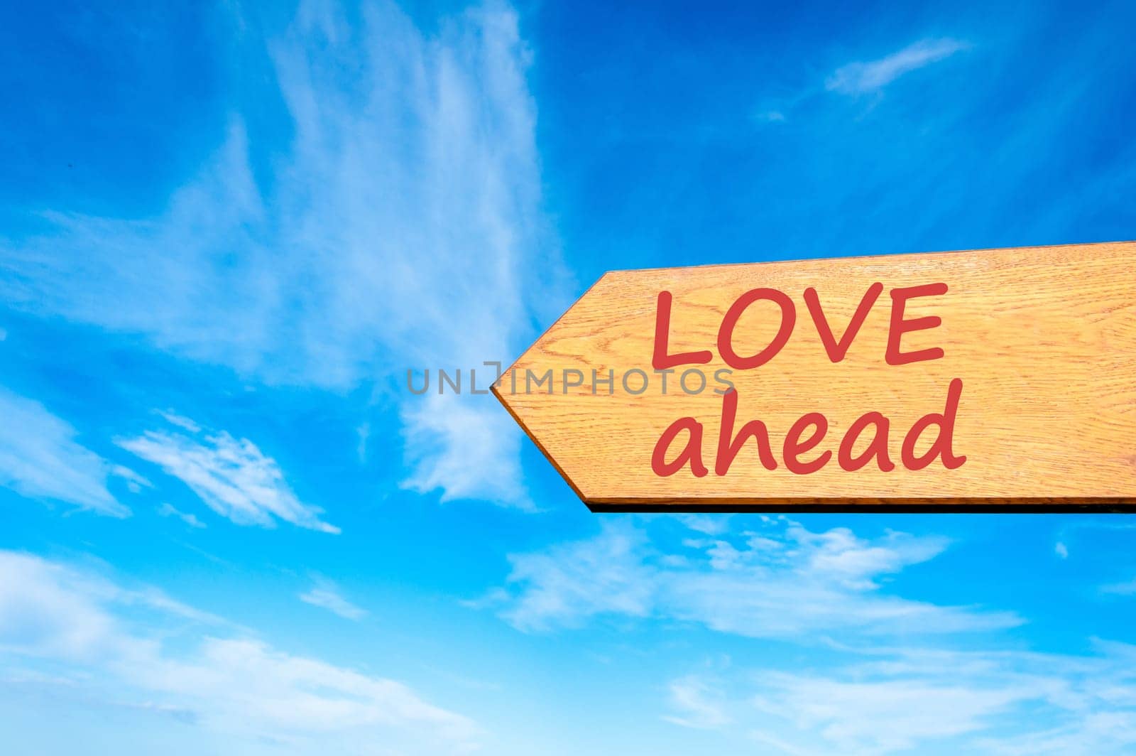 Wood arrow sign against clear blue sky with Love ahead message, Emotion and feelings concept