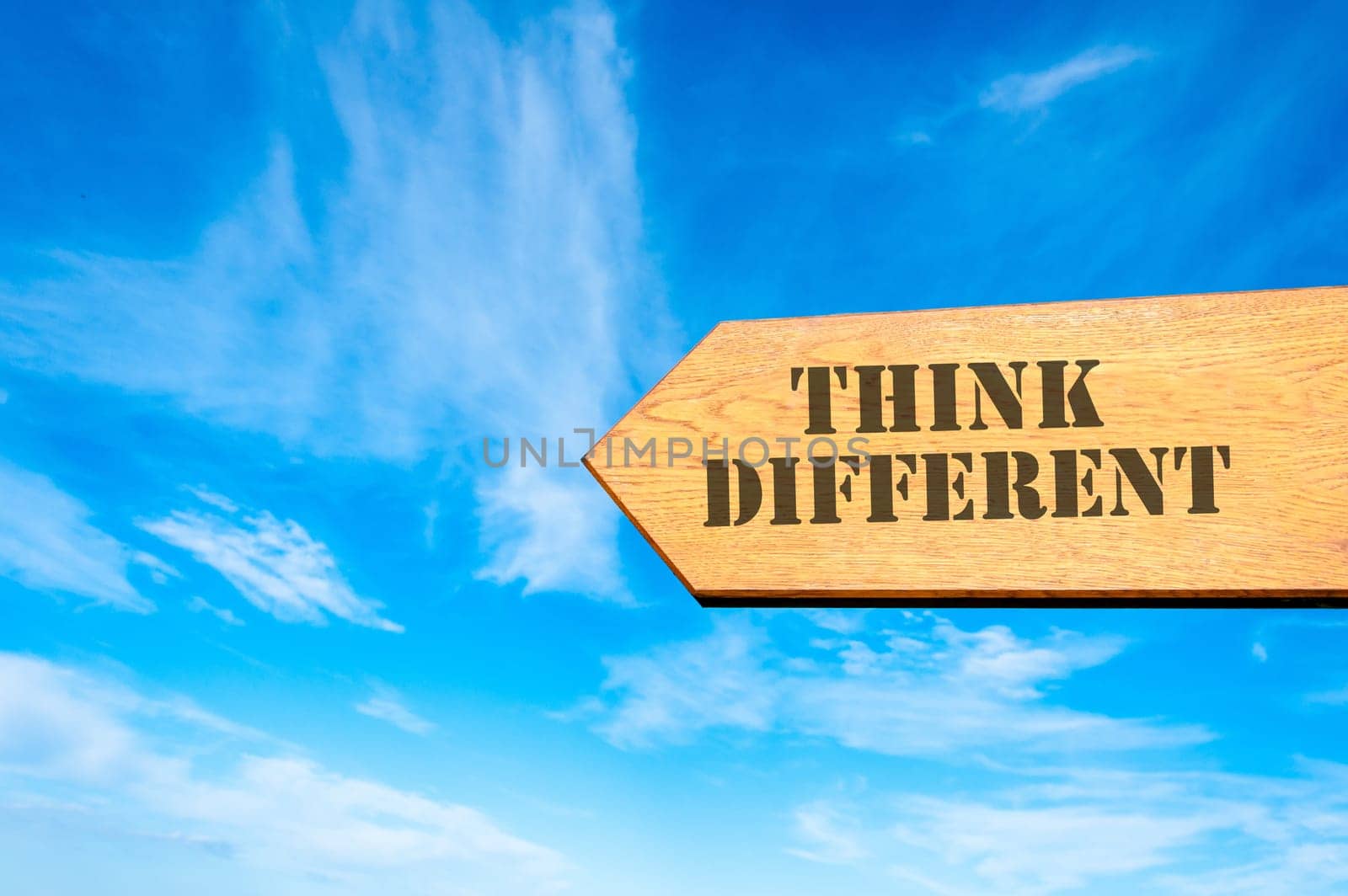 Wood arrow sign against clear blue sky with Think Different message, Business Vision concept