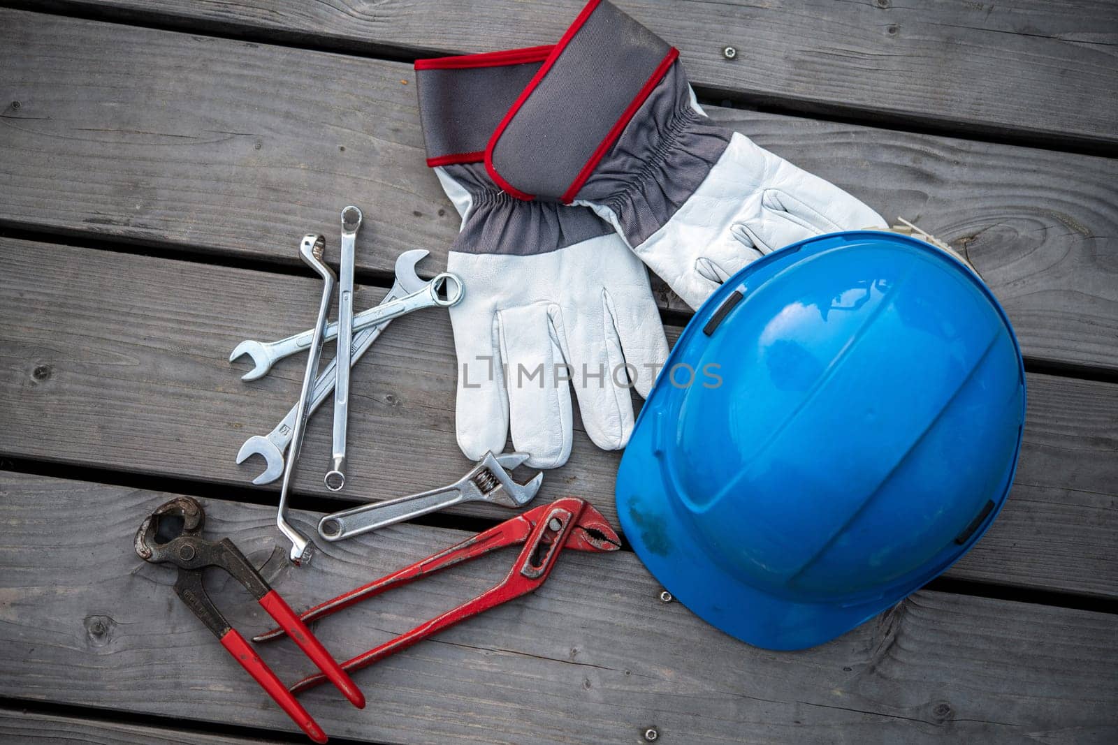 blue helmet different tools and work gloves on wooden ground