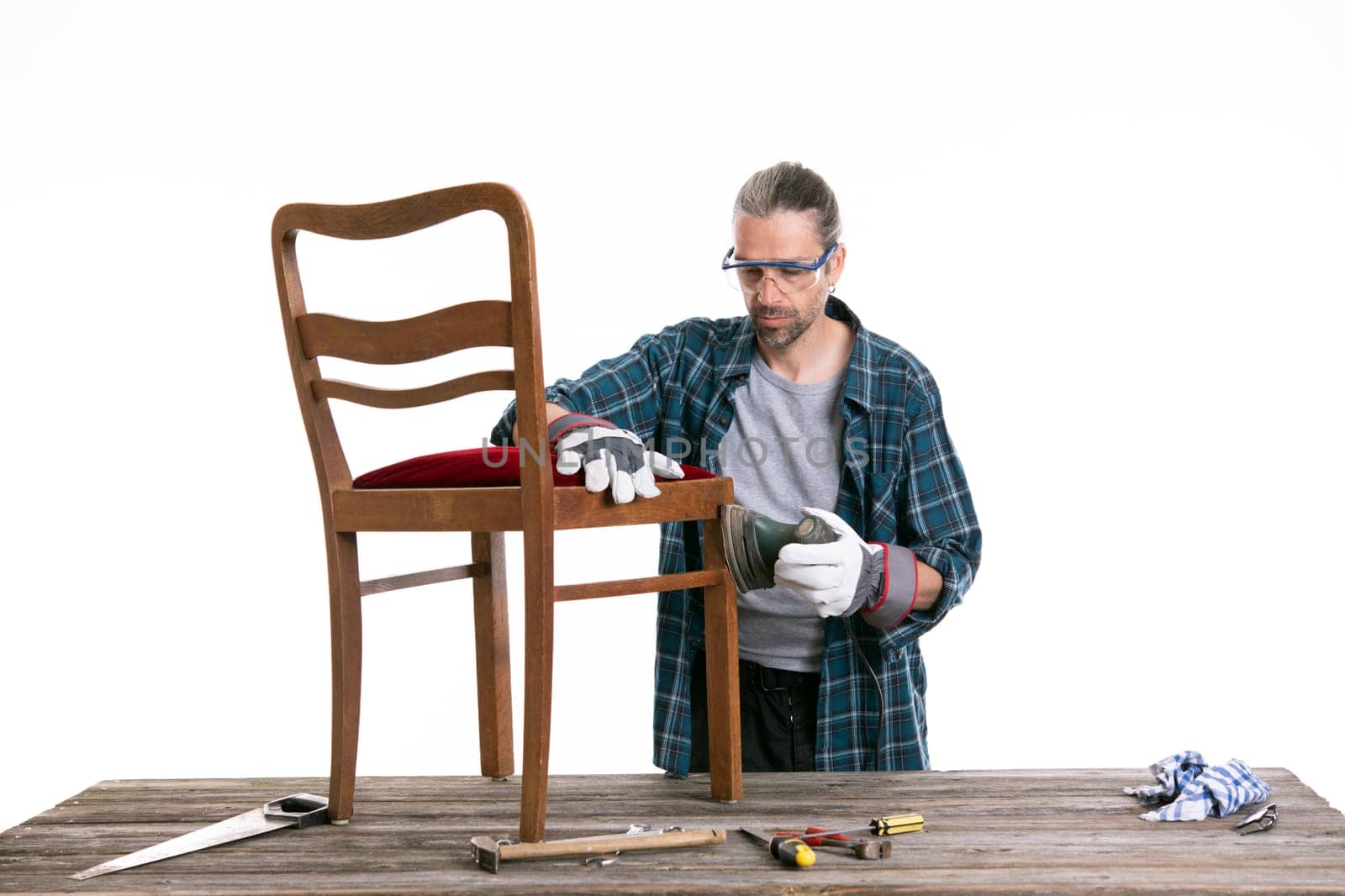 worker in blue plaid shirt repair old chair