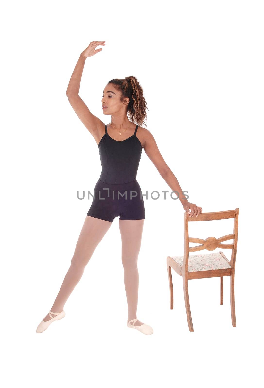 A lovely slim young woman in a black ballet outfit praxis some.movements for her ballet dancing, isolated for white background.