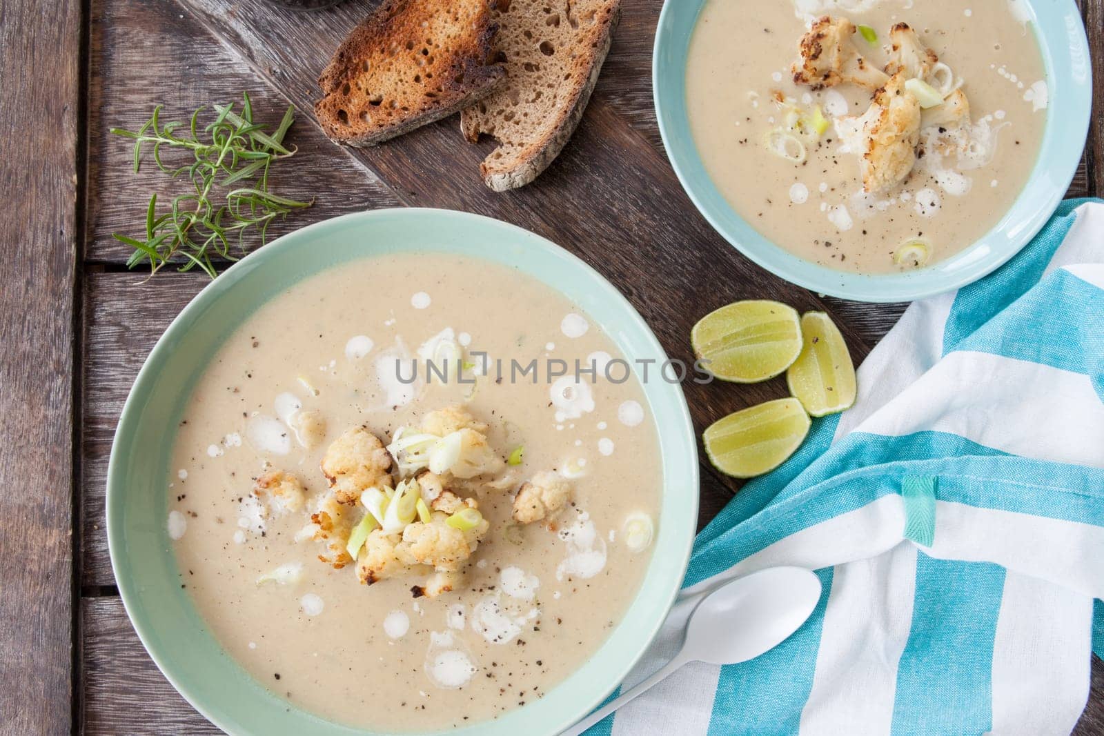Plate of creamy soup with roasted cauliflower and spring onions