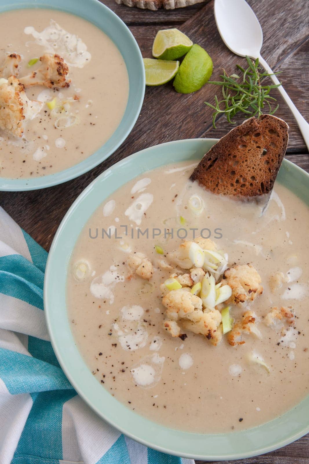 Plate of creamy soup with roasted cauliflower and spring onions
