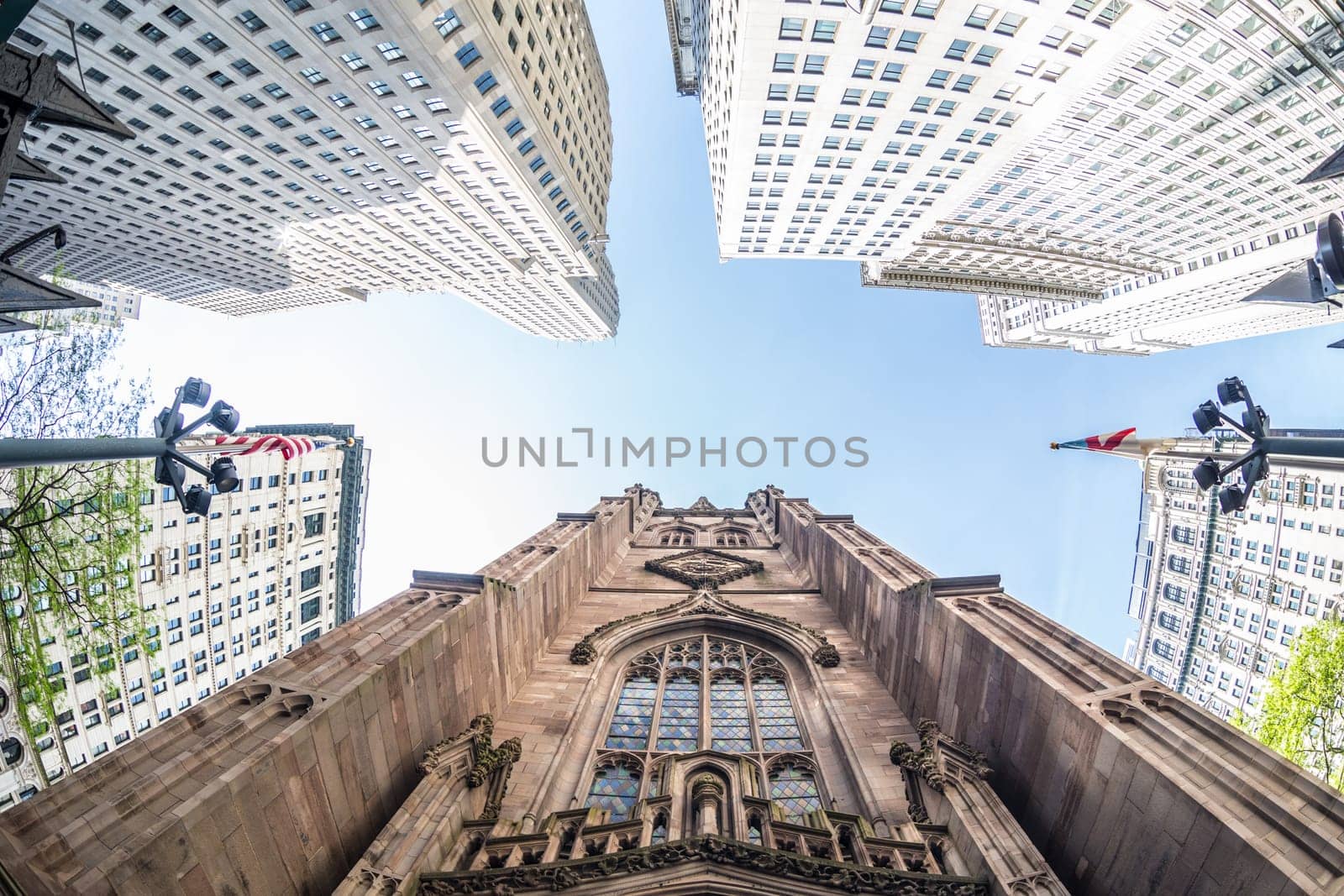 Wide angle upward view of Trinity Church at Broadway and Wall Street with surrounding skyscrapers, Lower Manhattan, New York City, USA.