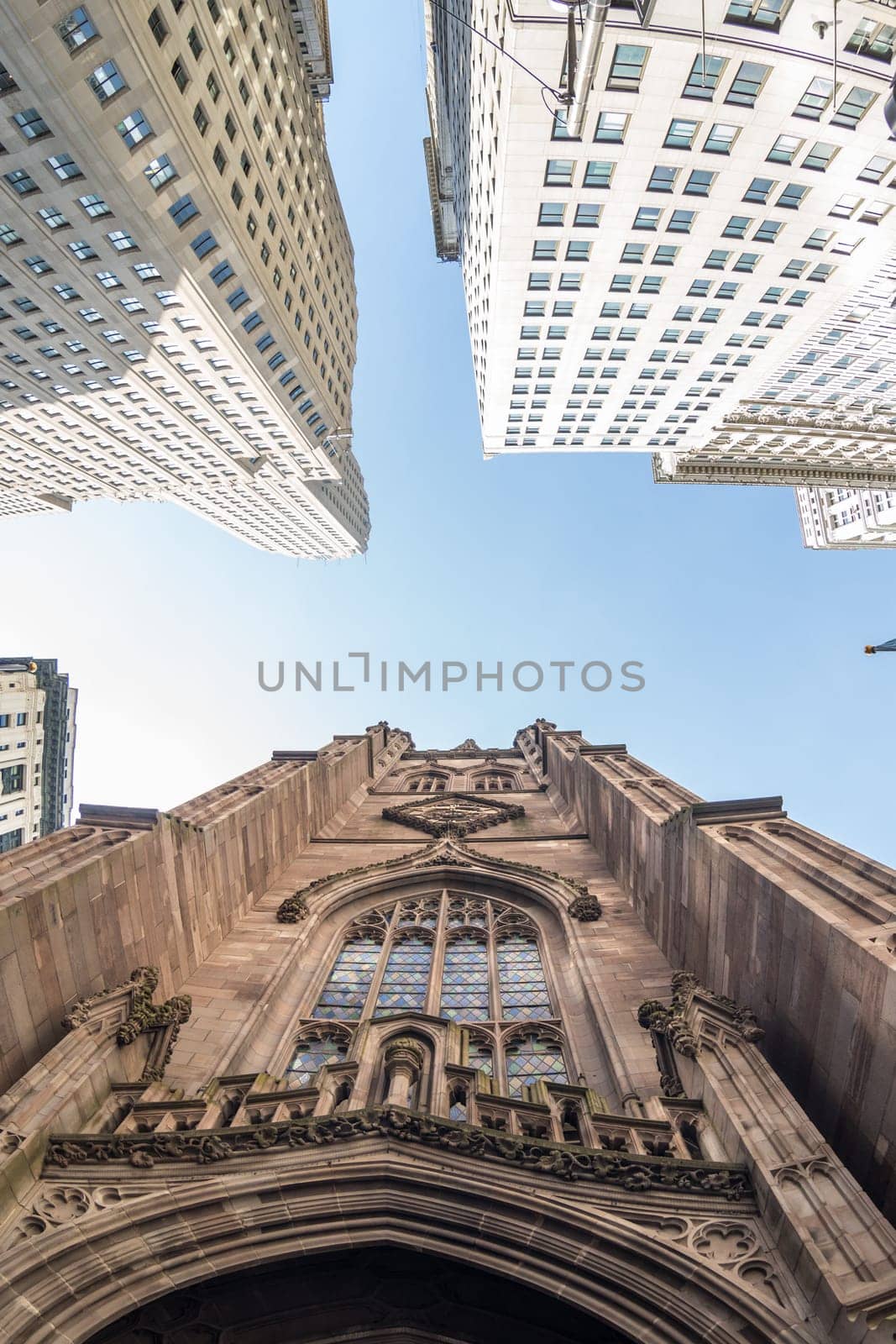 Wide angle upward view of Trinity Church at Broadway and Wall Street with surrounding skyscrapers, Lower Manhattan, New York City, USA.