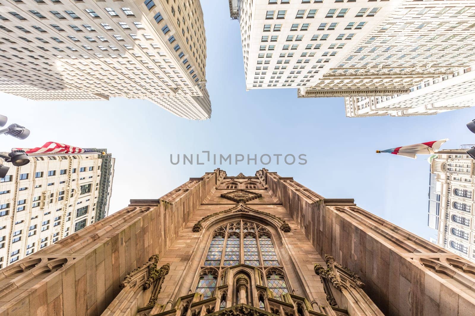 Wide angle upward view of Trinity Church at Broadway and Wall Street with surrounding skyscrapers, Lower Manhattan, New York City, USA.