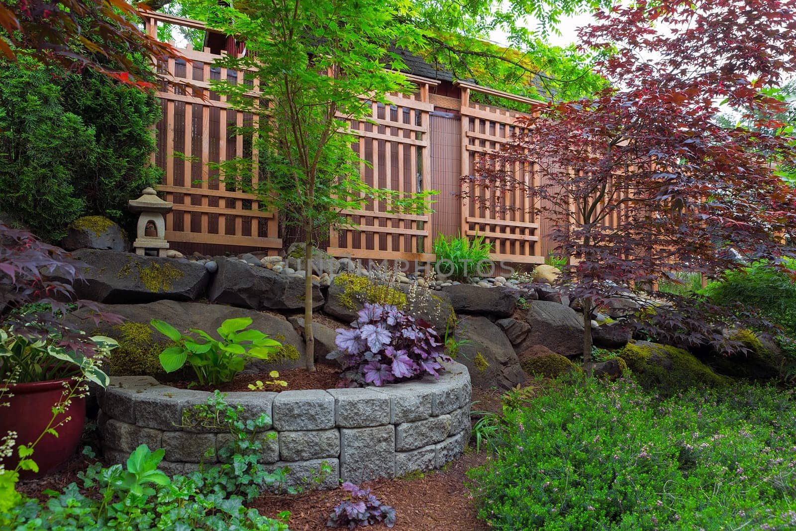 Home garden backyard landscaping with natural and stone stacked planter pots trellis lantern trees shrubs plants