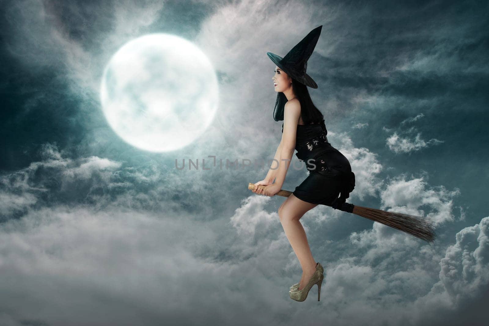 Happy asian witch woman flying above a broomstick with full moon background