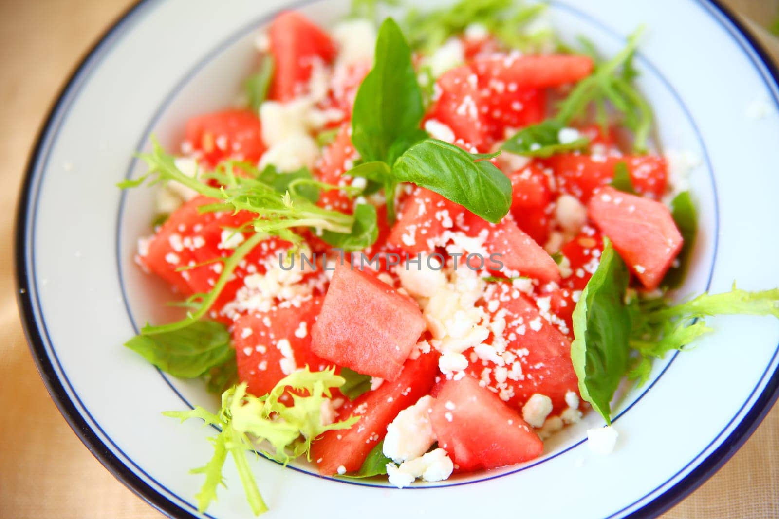 Overhead of cooling melon salad with feta cheese and fresh basil