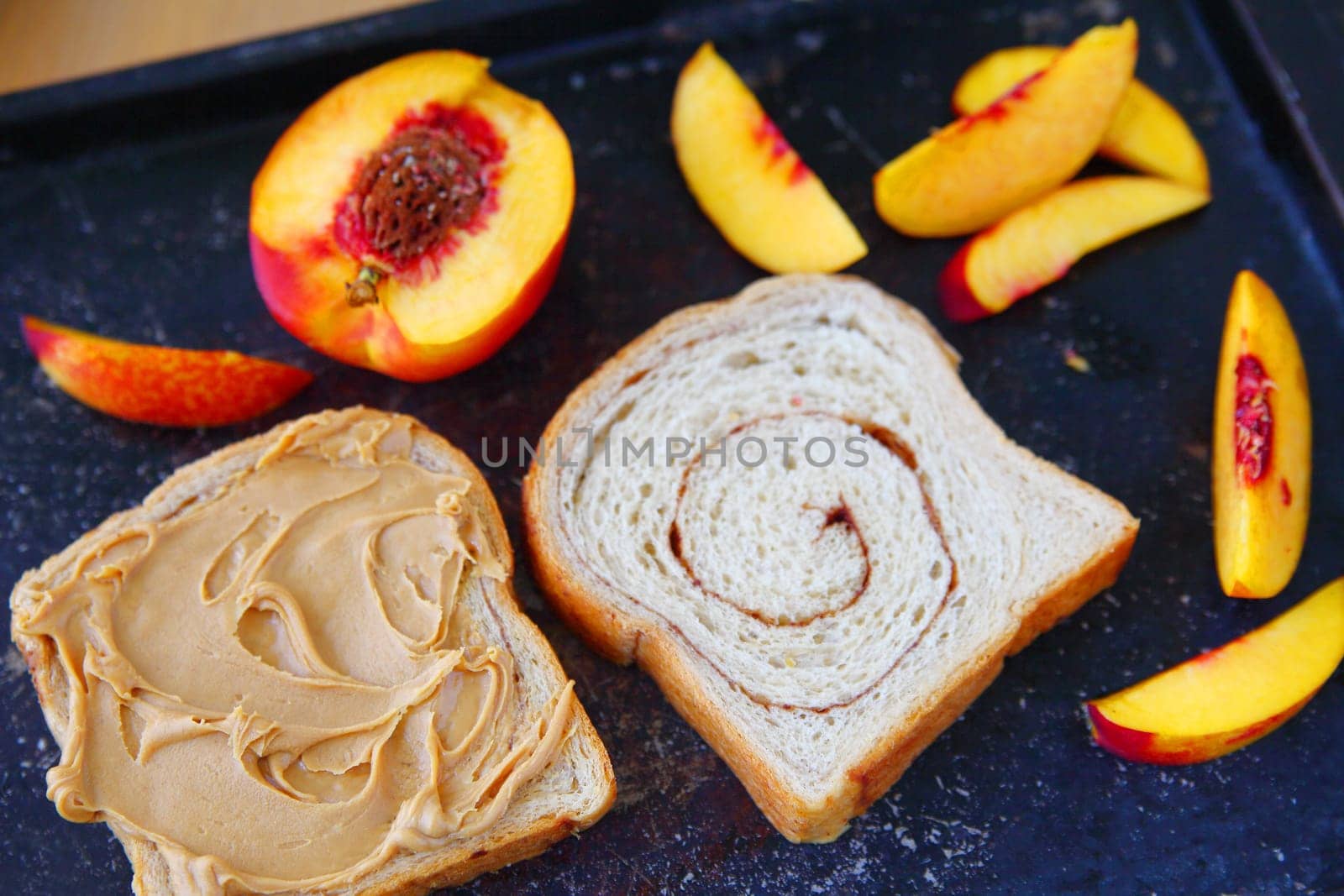 Making a sandwich with peanut butter and fresh fruit on cinnamon swirl bread