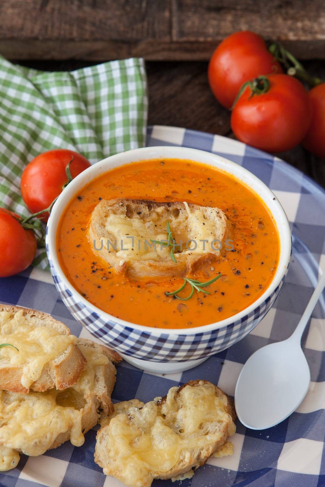 Hearty tomato soup with rosemary and slices of cheese baguette