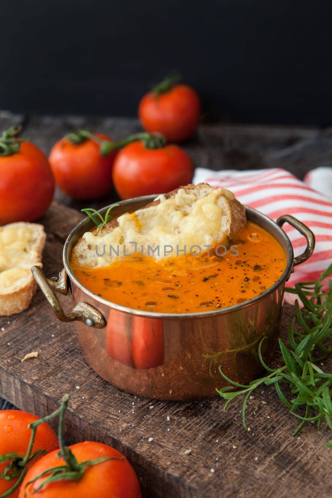 Hearty tomato soup with rosemary and slices of cheese baguette
