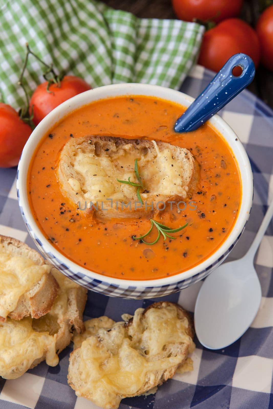 Hearty tomato soup with rosemary and slices of cheese baguette