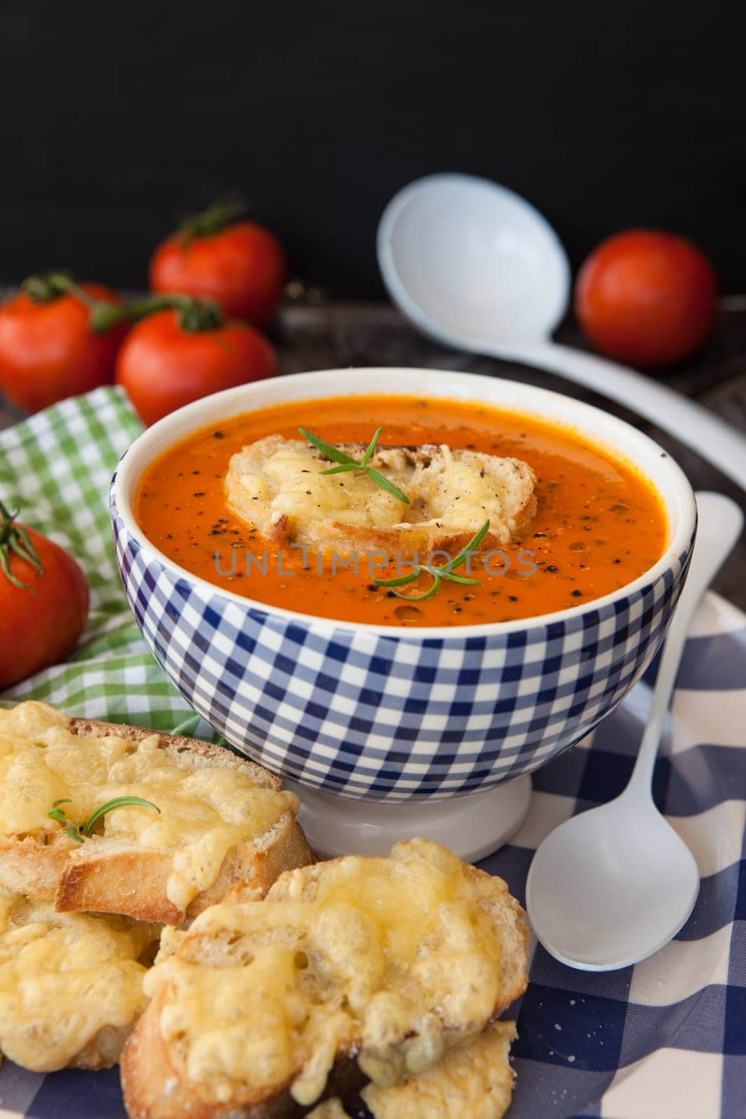 Hearty tomato soup with rosemary and slices of cheese baguette
