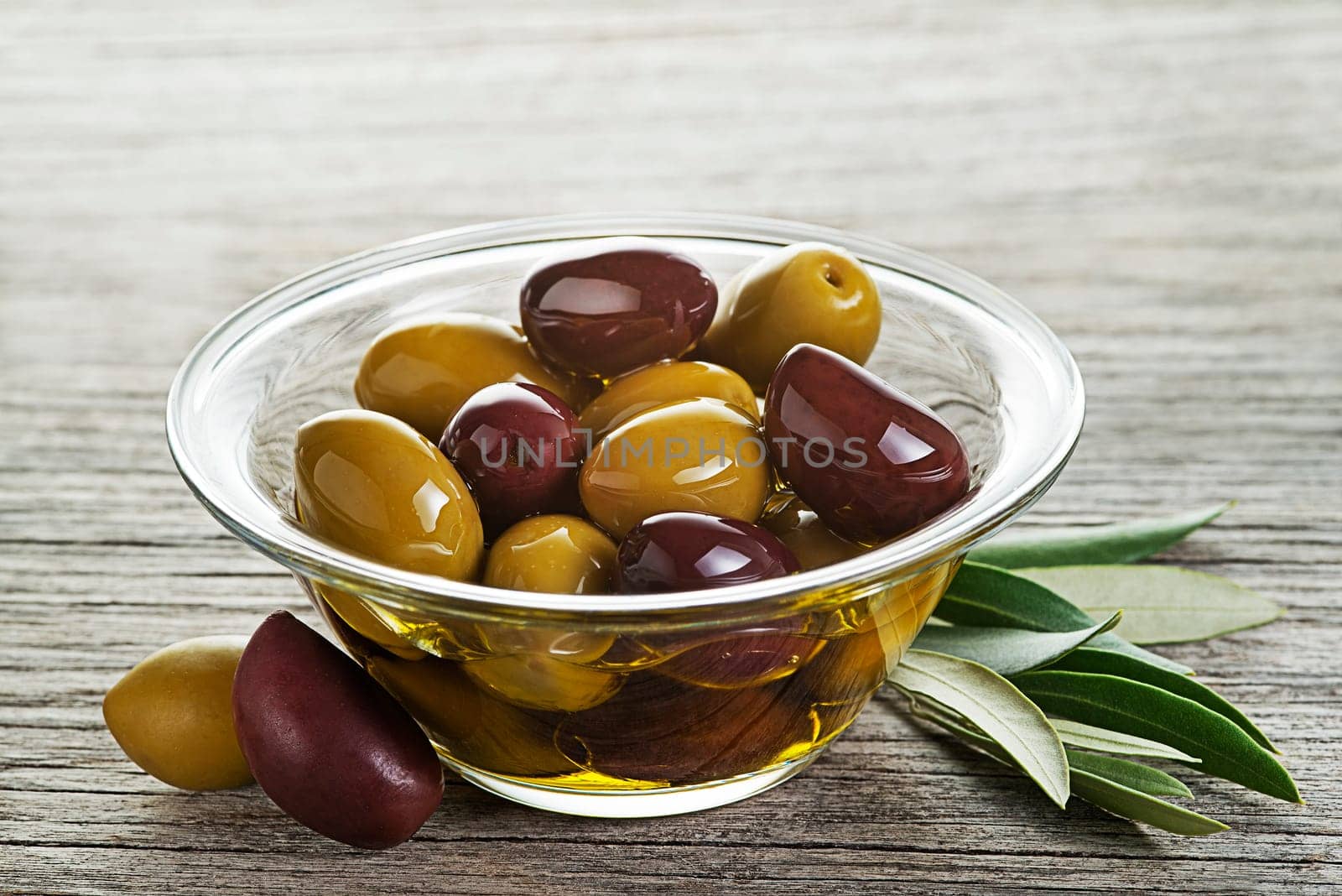 Bowl of virgin olive oil with olives close up