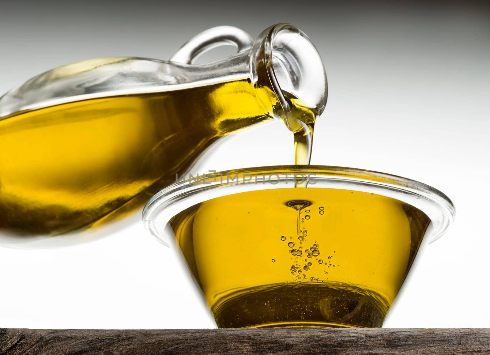 Bottle pouring olive oil in a bowl close up